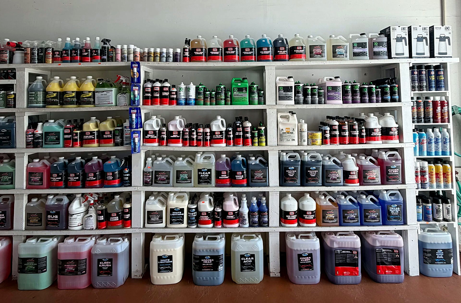 Full shelves of gallon jugs, bottles and 5-gallon detailing chemicals inside Expert Detail Supply